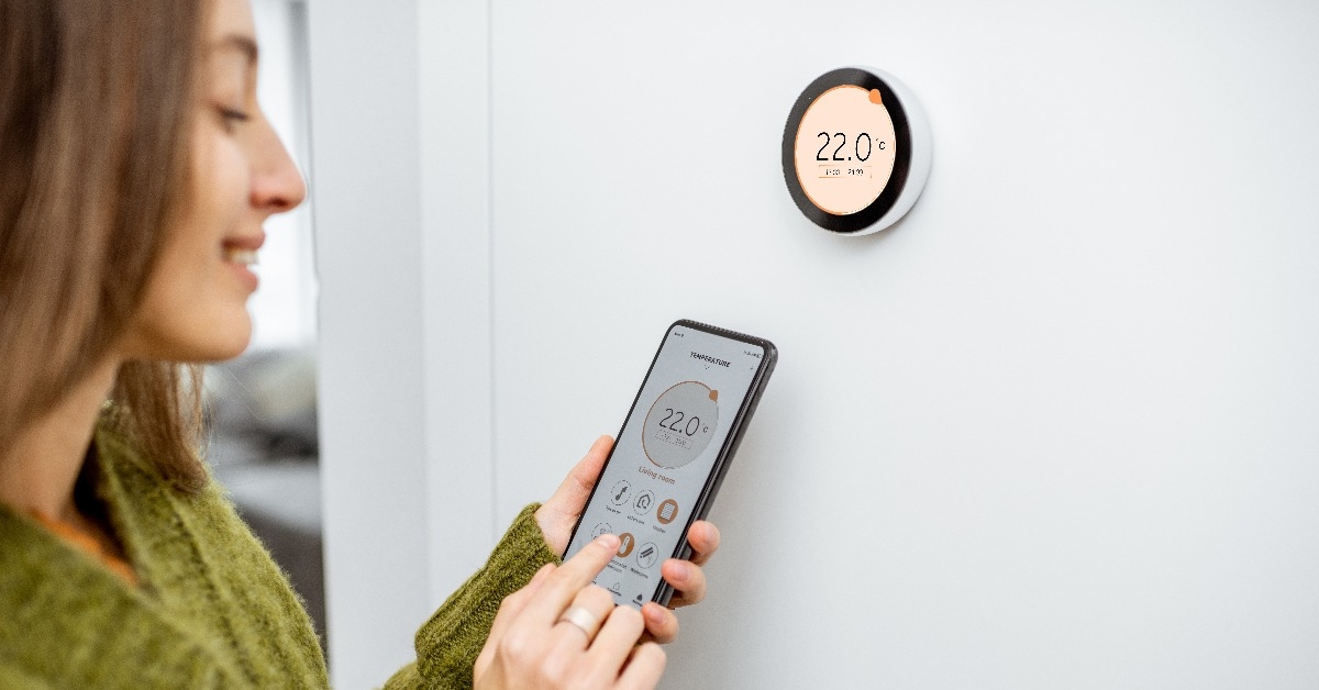 woman dressed in green sweater regulating heating temperature