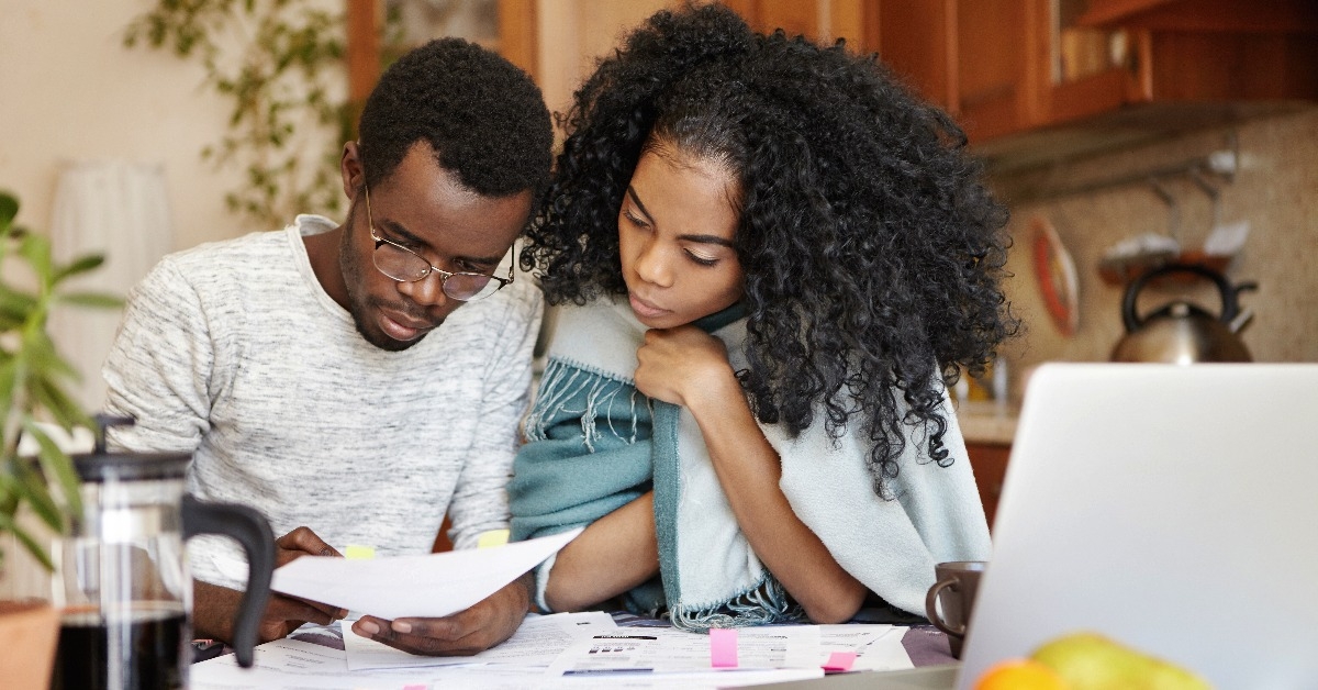 male holding piece of paper while paying gas and electricity bills online on notebook pc