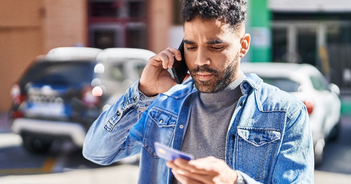 man talking on the smartphone and using credit card at street