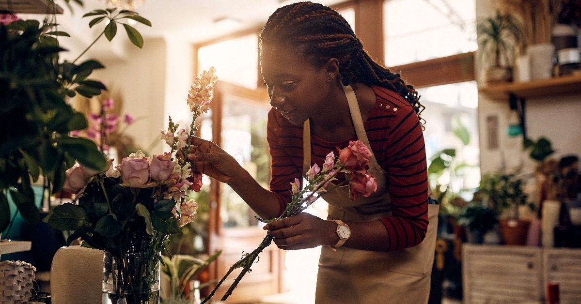 creative black florist arranging flowers while working at her flower shop