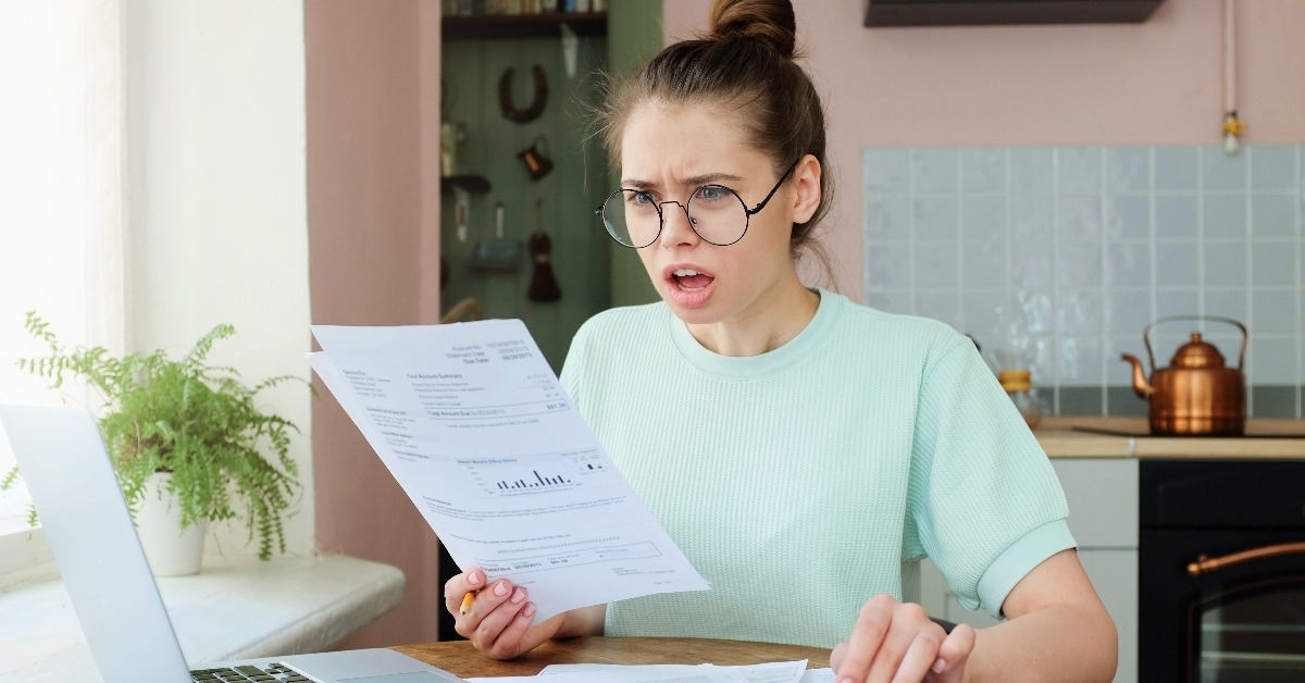 emotional European lady dealing with sheets of paper and bills at home
