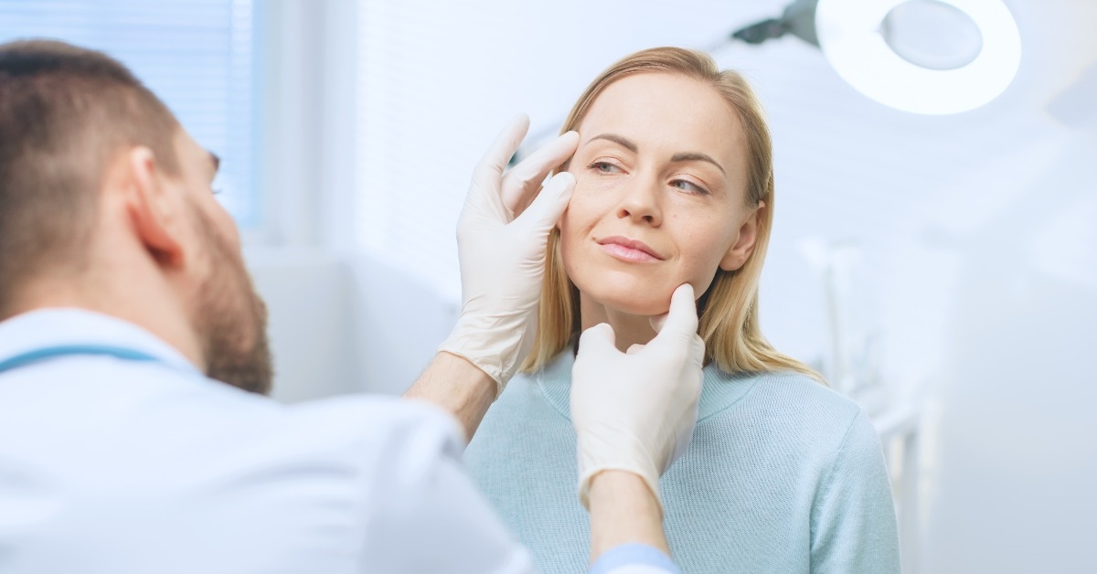 cosmetic surgeon examines beautiful woman's face