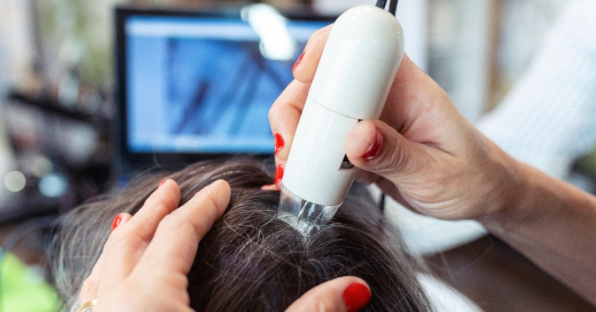 hairdresser examining client hair with a special apparatus for diagnostic hair