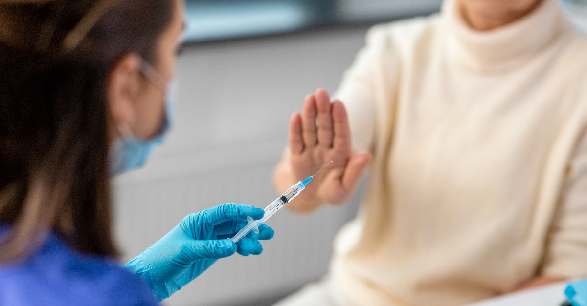nurse with syringe and senior woman refusing from vaccine