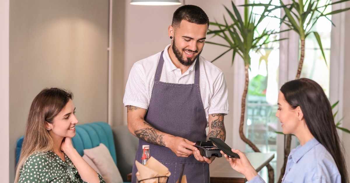 woman paying bill in restaurant through terminal