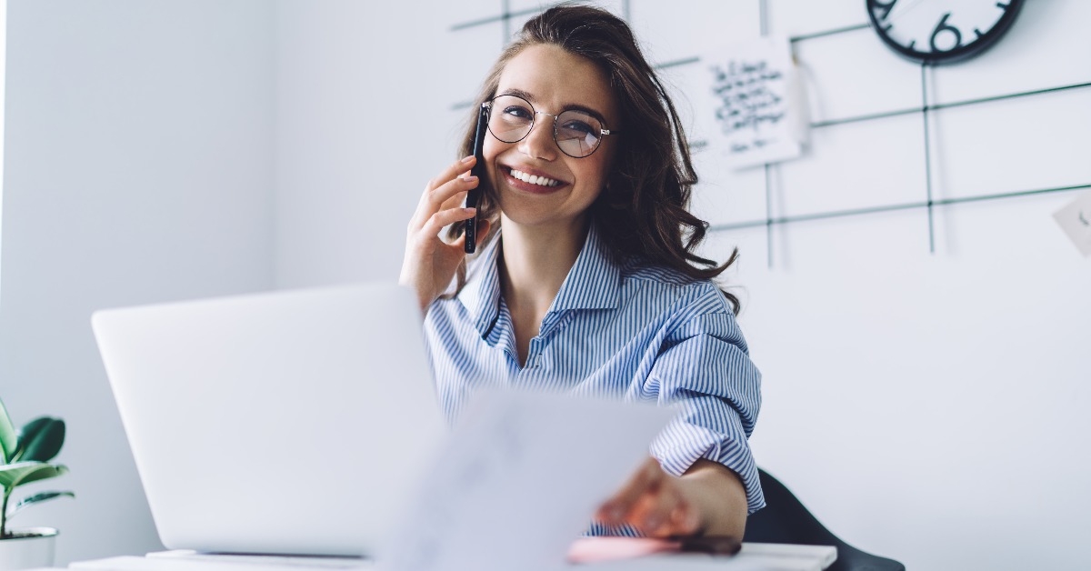 young woman laughing while talking on cellphone in office