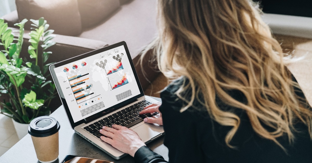  businesswoman is sitting at table working on laptop with graphs