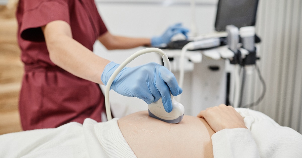 female doctor holding ultrasound transducer to pregnant belly