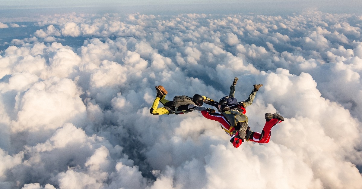 group of skydivers above the clouds