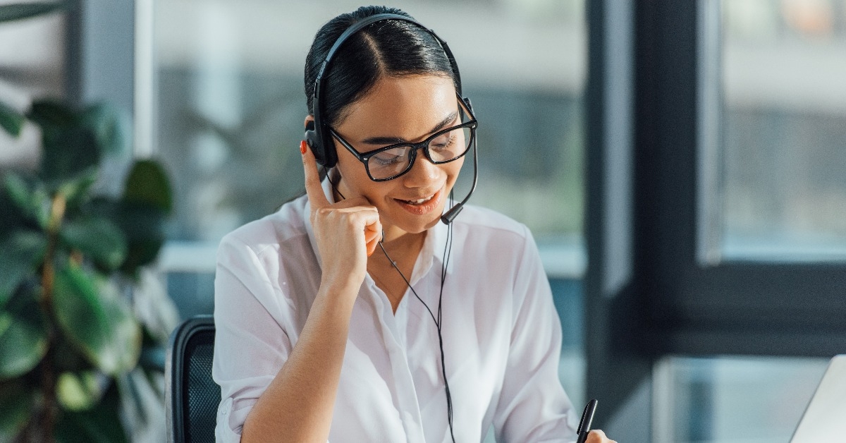 asian translator working online with headset and laptop in office