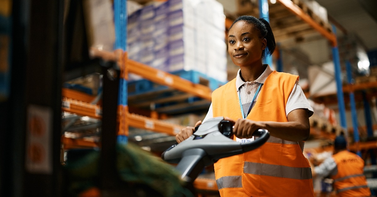 female worker pushing cargo on pallet jack
