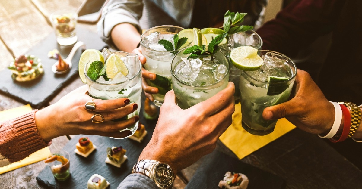 happy friends group cheering mojito drinks at cocktail bar restaurant