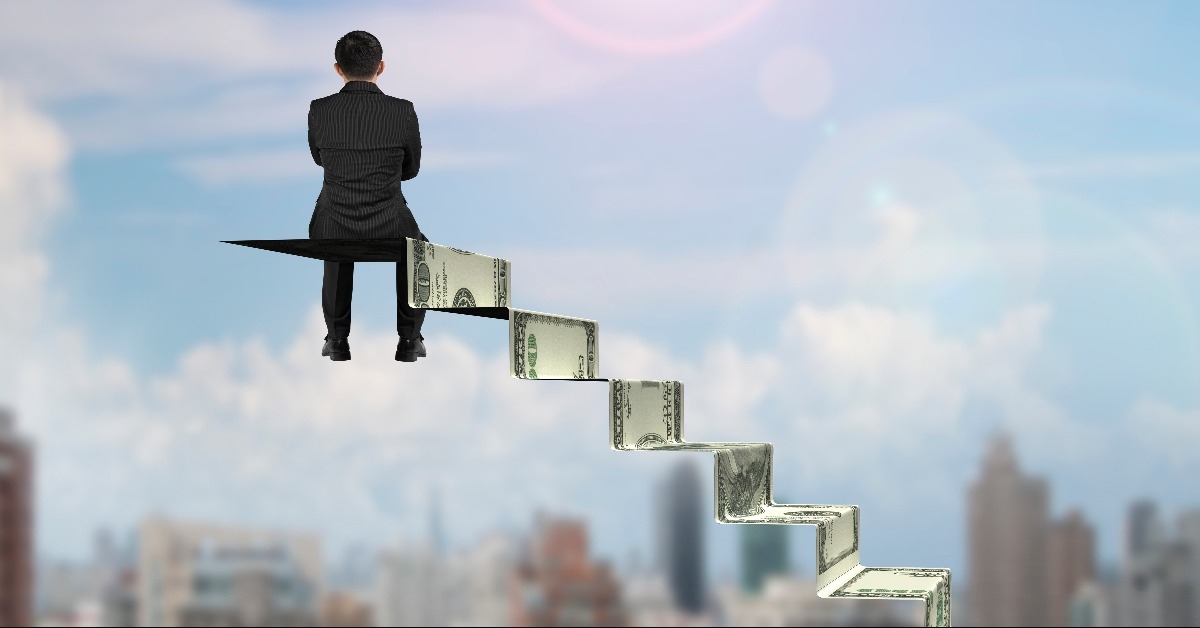 businessman sitting on top of money stairs
