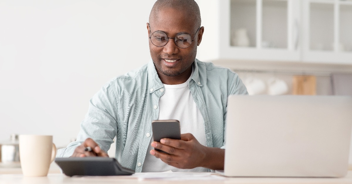 black man using calculator phone and laptop