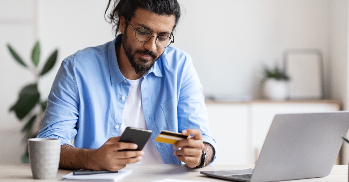 freelancer guy using smartphone and credit card at home