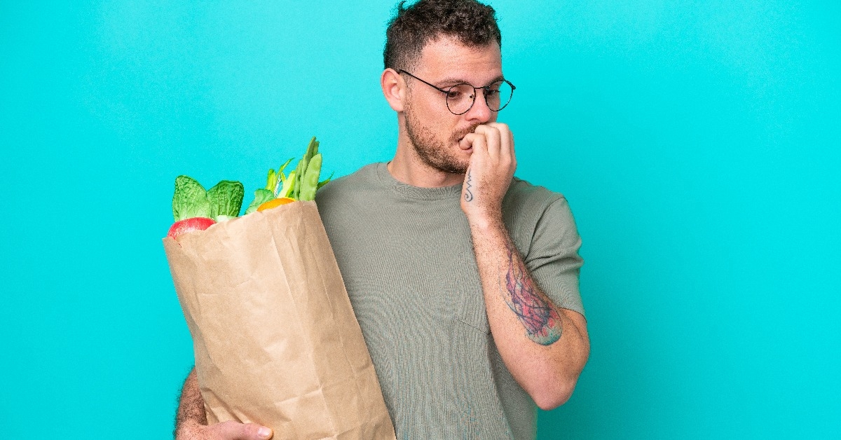 man having doubts holding a grocery shopping bag