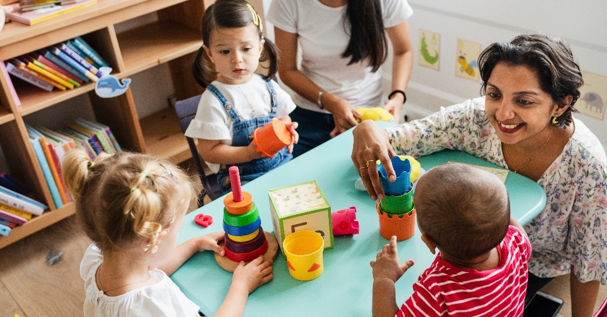nursery children playing with teacher in the classroom 
