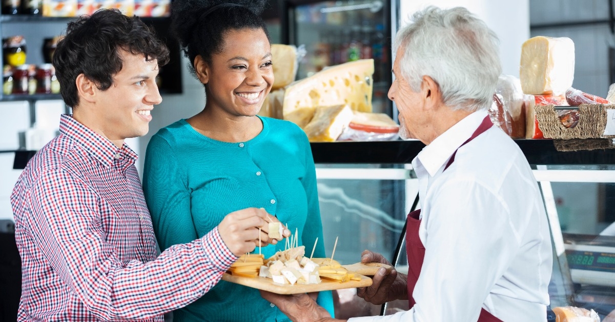 salesman offering cheese samples to customers in shop