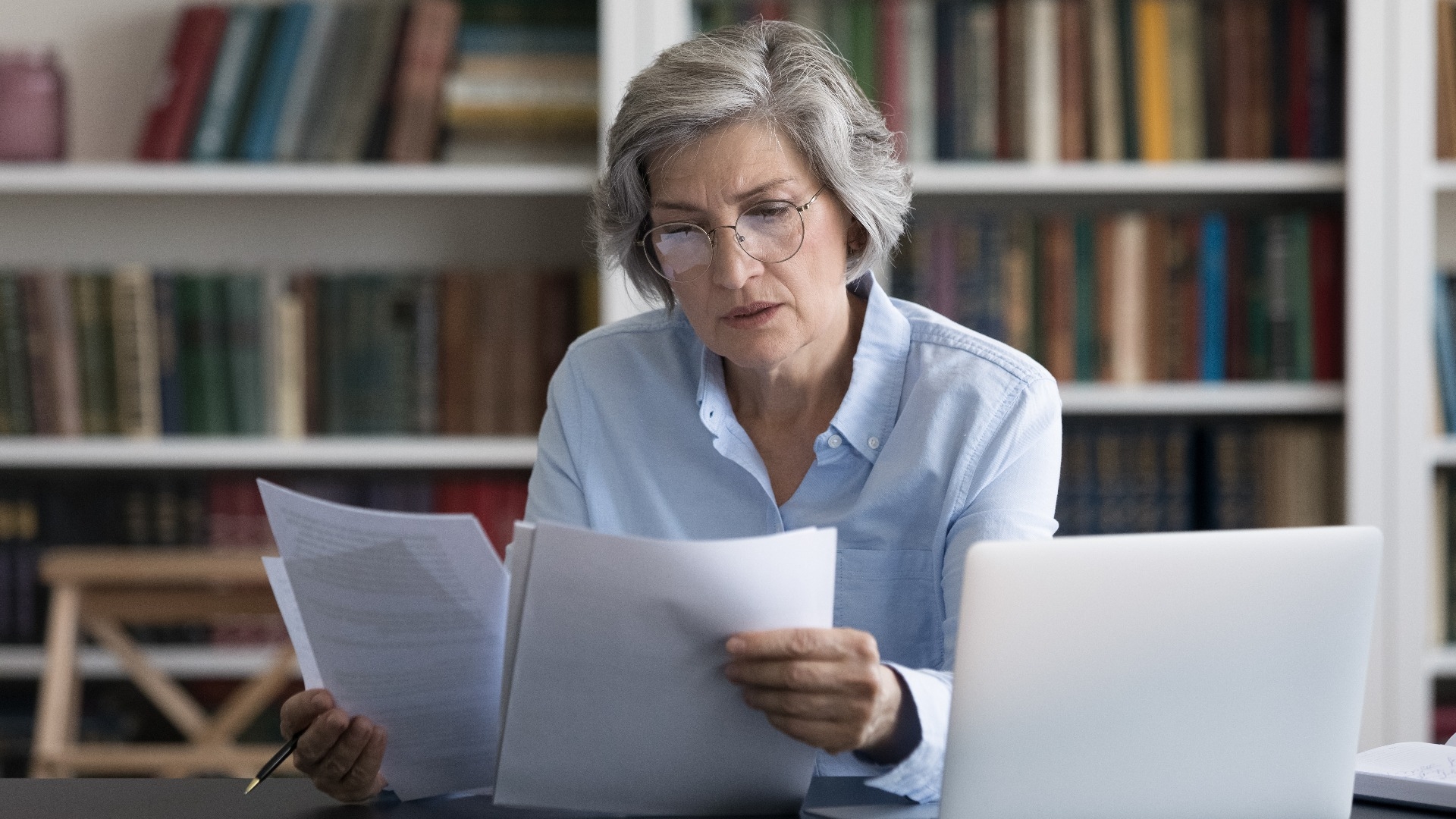 middle aged woman in glasses looks worried reading news 
