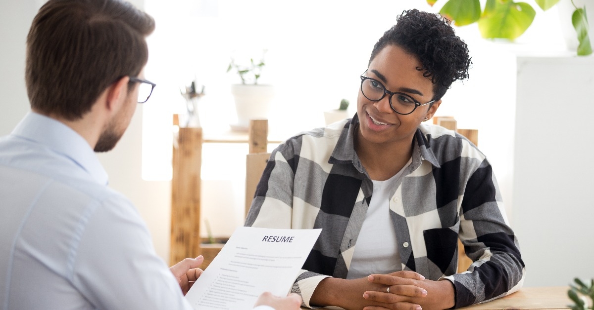 male employer holding resume while talking to a female job candidate