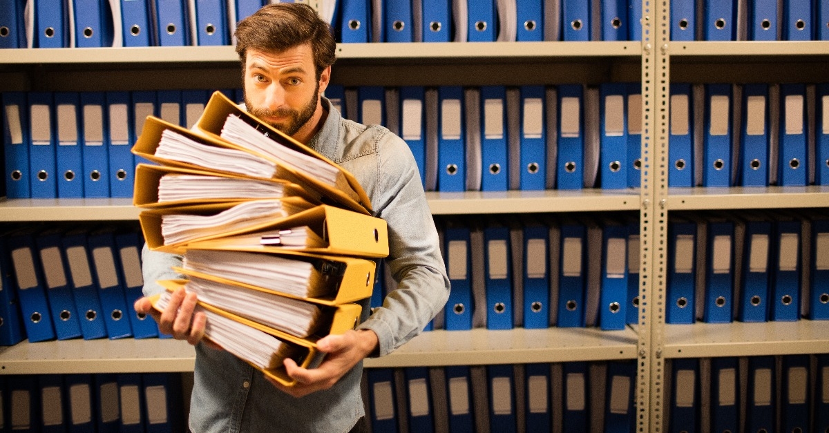 businessman holding stack of files in storage room