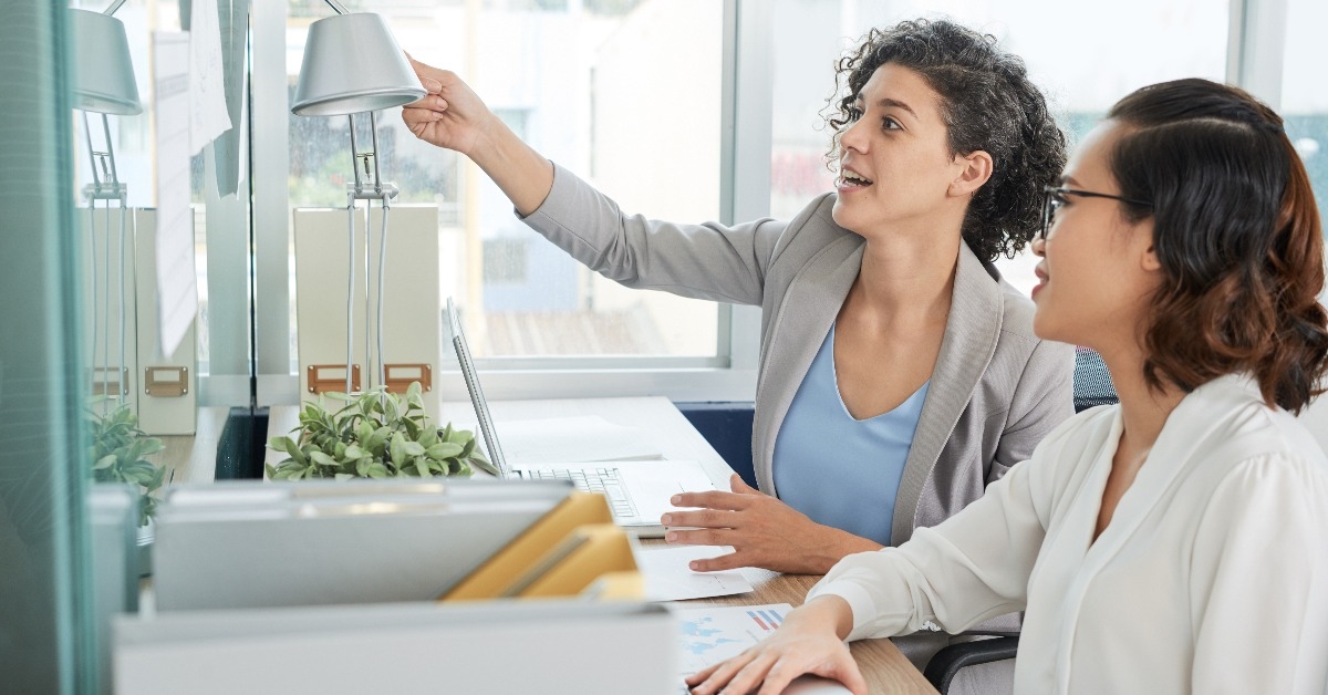 multi-ethnic businesswomen discussing notes hanging on the wall