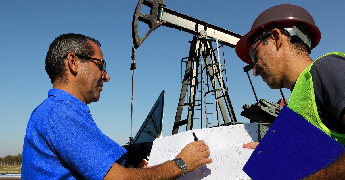 petroleum engineers with laptop and blueprint