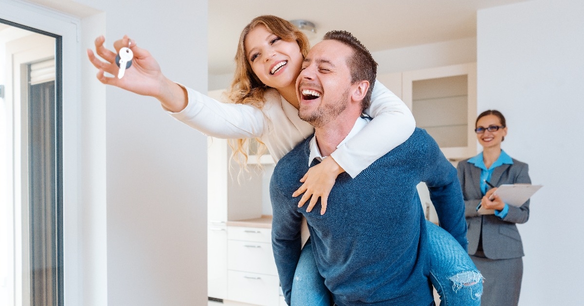 man carrying his wife piggyback who is showing the house keys