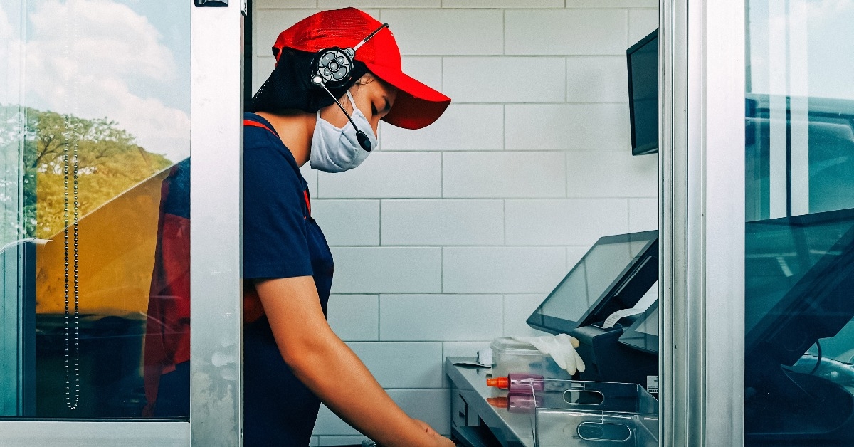 fast food cashier in drive thru service wearing hygiene face mask
