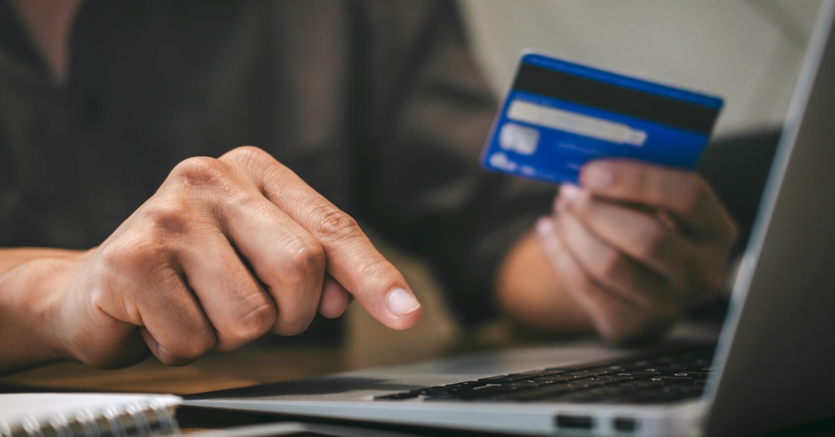 man on laptop holding credit card 
