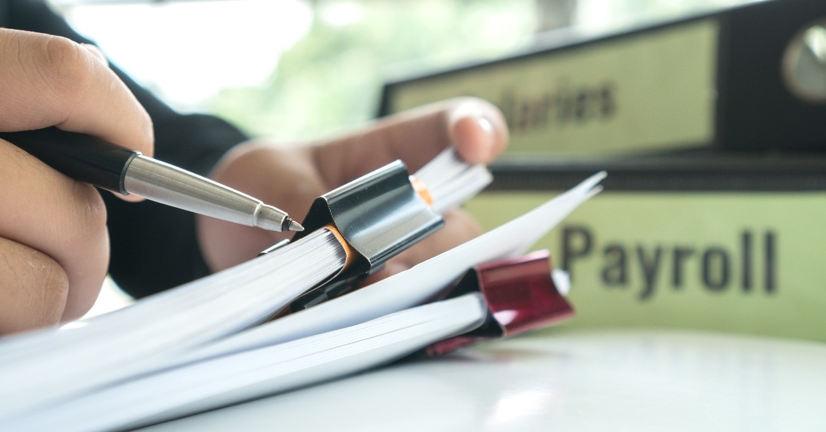 signing paperwork near payroll salary binder