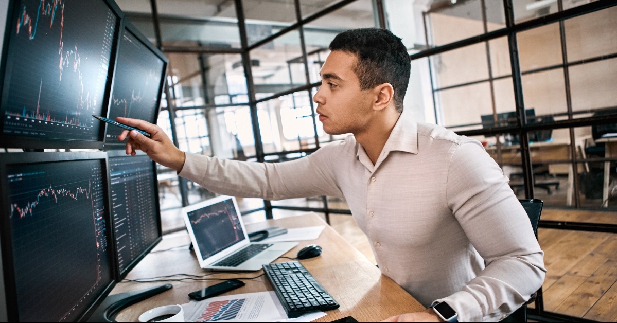 trader sitting at office in front of monitors