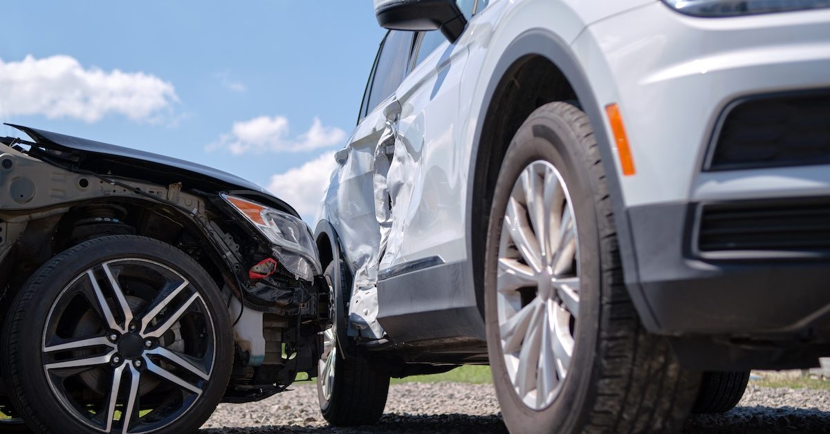 Two cars in a collision. One car is severely dented along the side. 