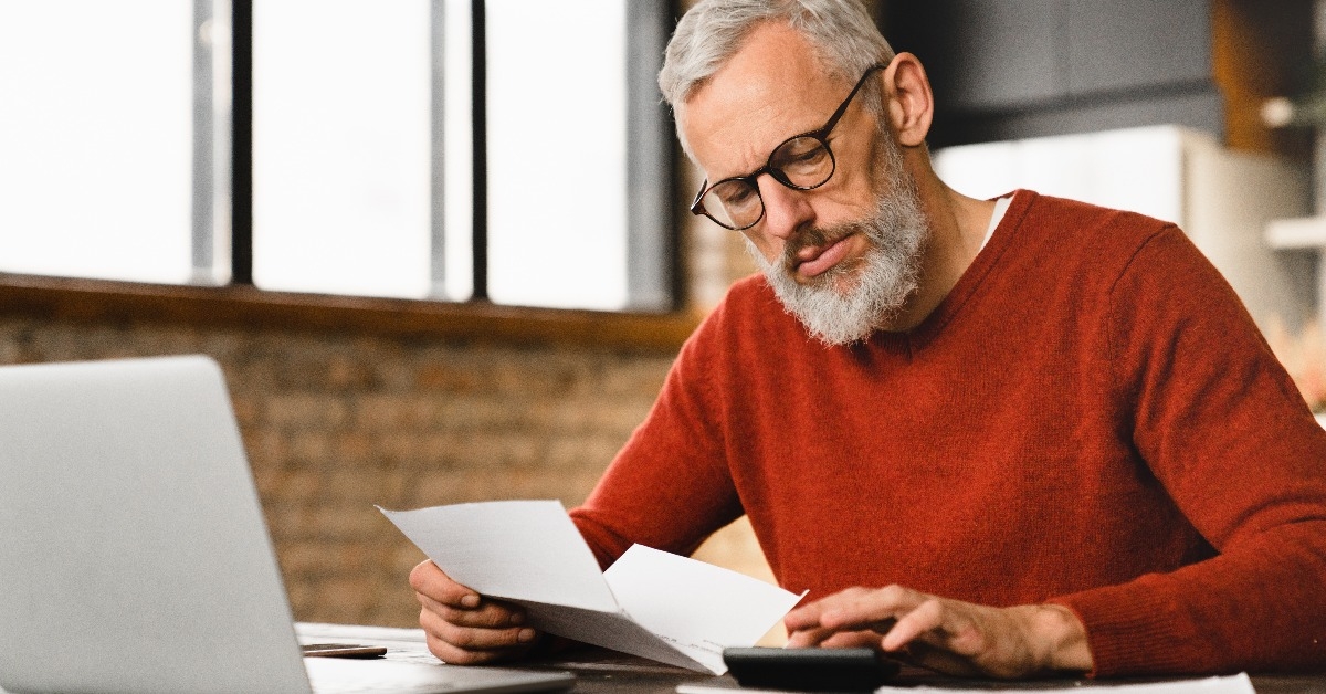 middle-aged businessman counting domestic bills on calculator