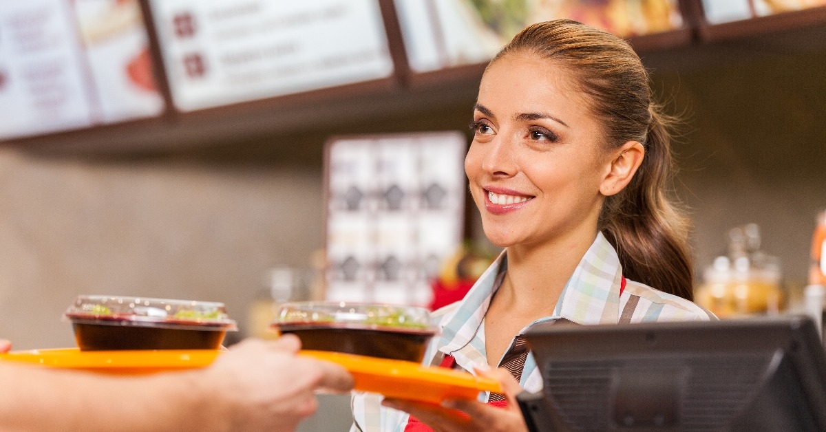 restaurant worker serving two fast food meals with smile