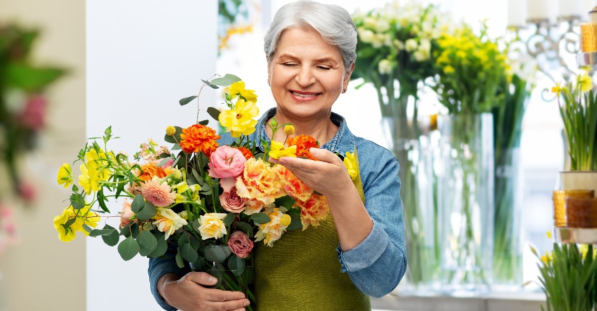 senior woman in green garden apron with bunch of flower
