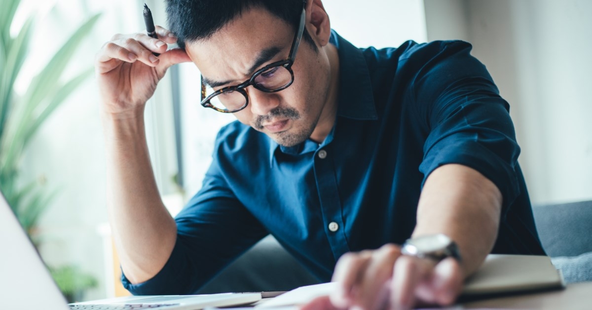 frustrated man working while holding a pen