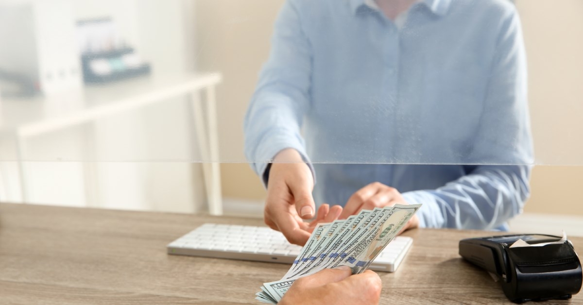 man giving money to a teller 