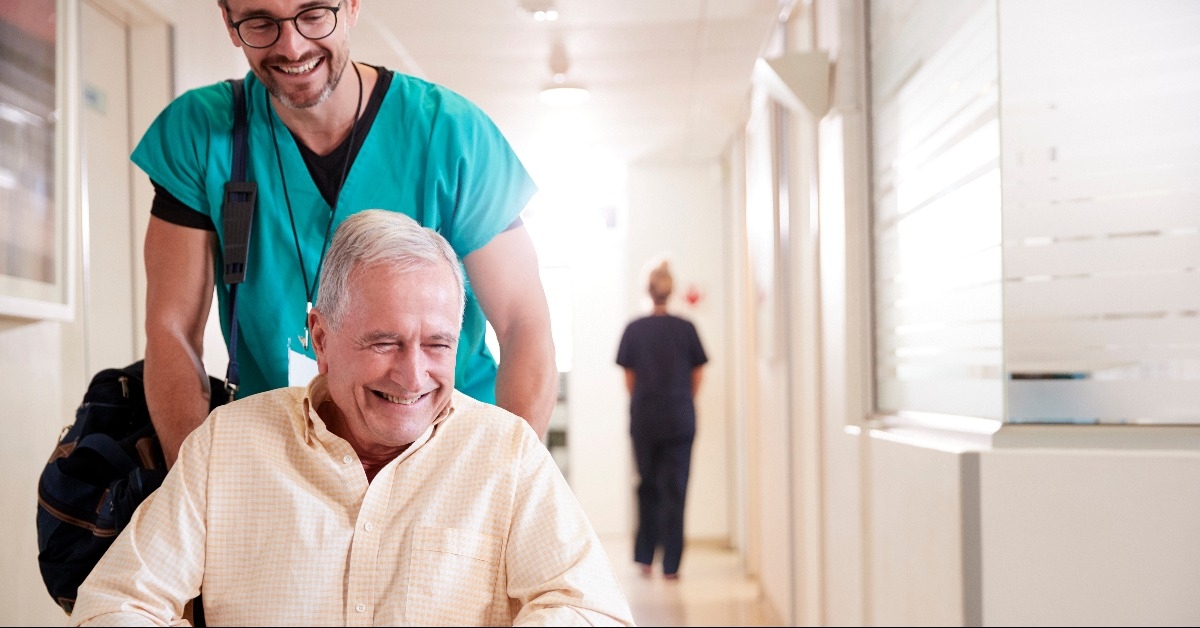 orderly pushing senior male patient being discharged from hospital