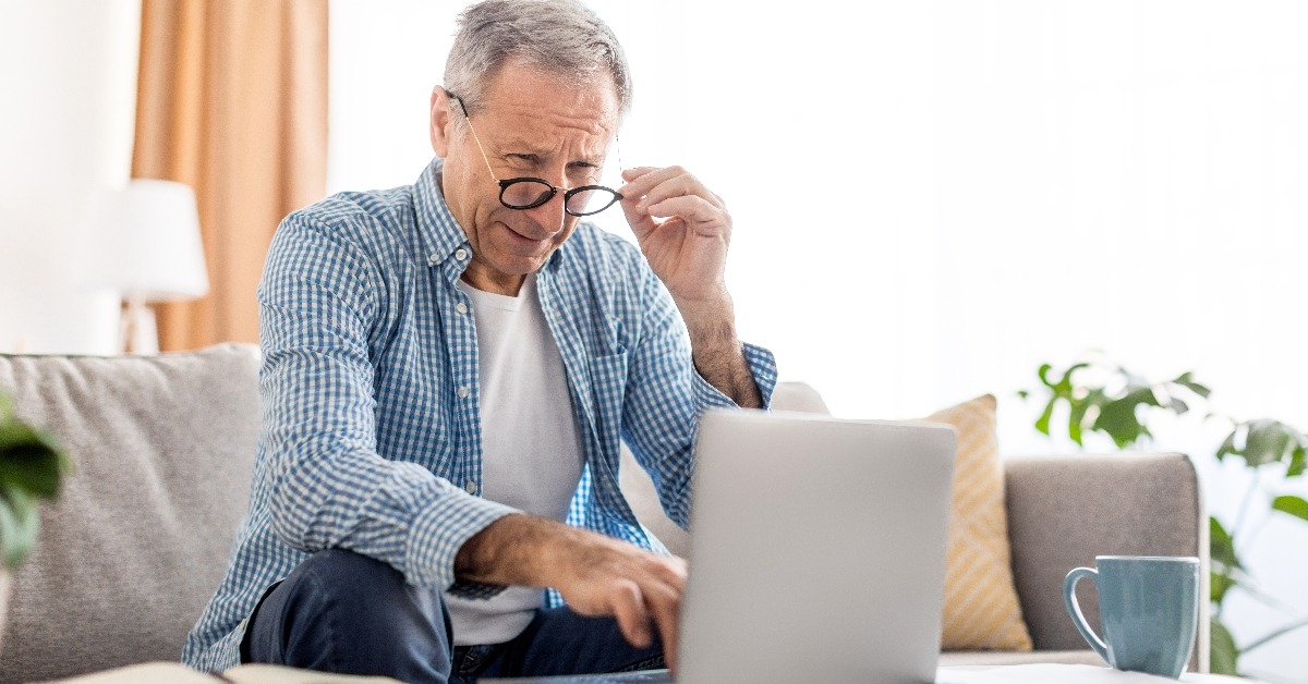 man squinting using laptop looking at pc screen