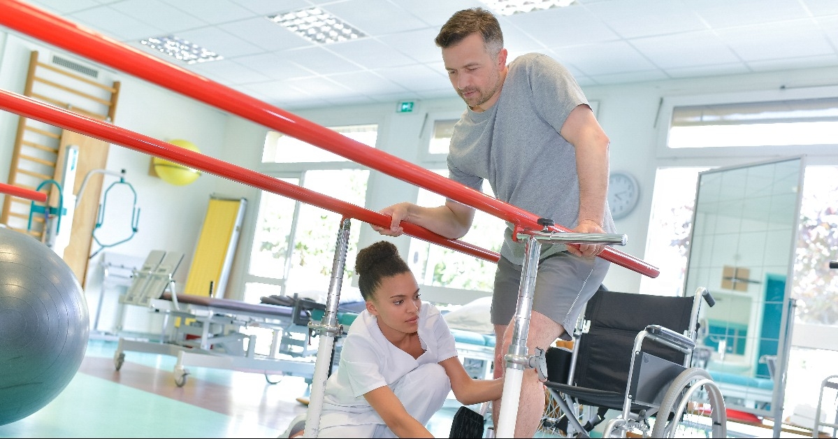 occupational therapist helping patient to walk