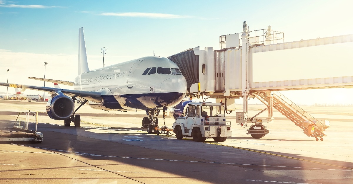  commercial plane on airfield docked with boarding bridge at sunrise