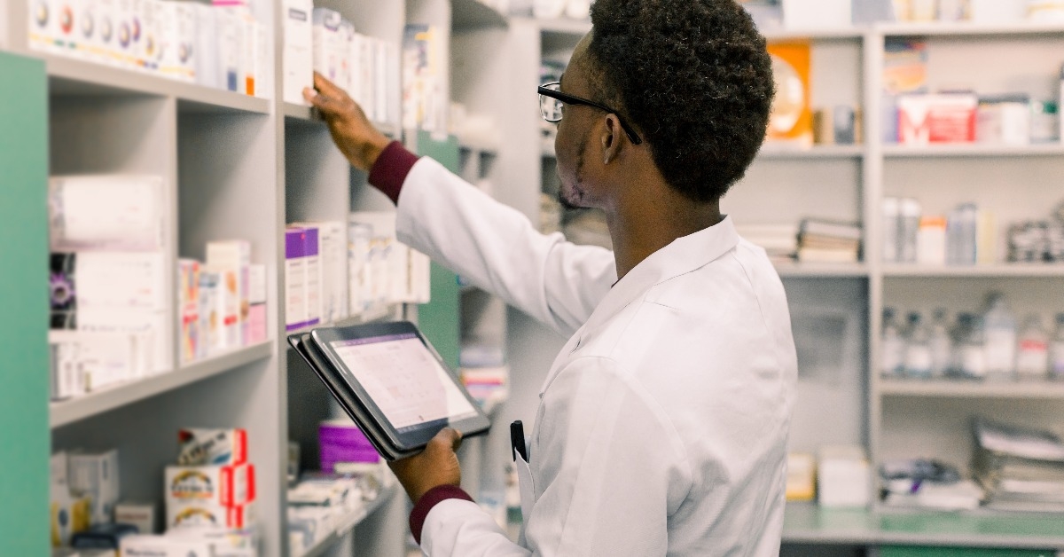 male pharmacist using digital tablet during inventory