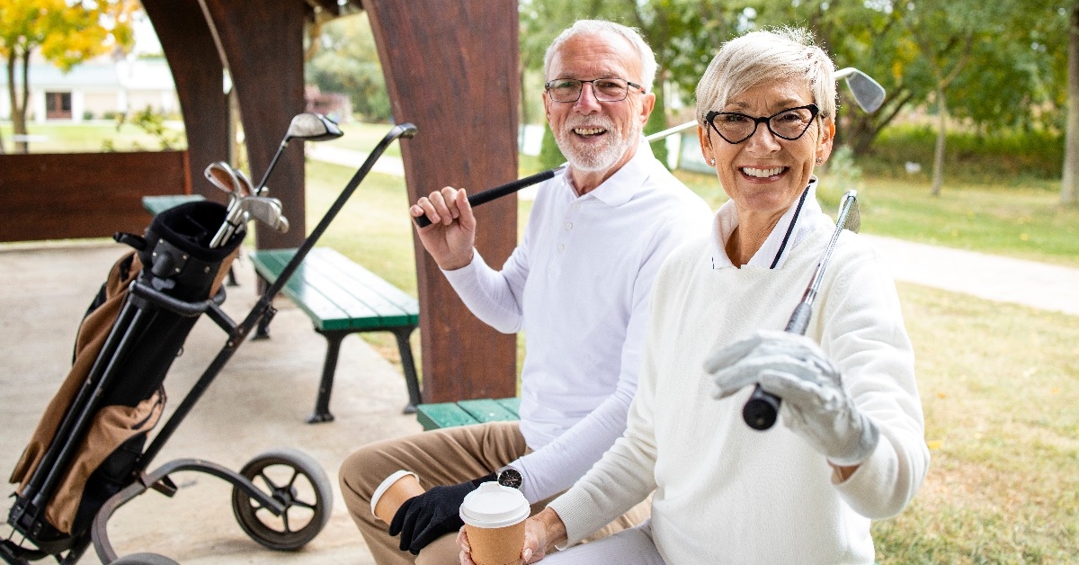 seniour couple holding golf clubs