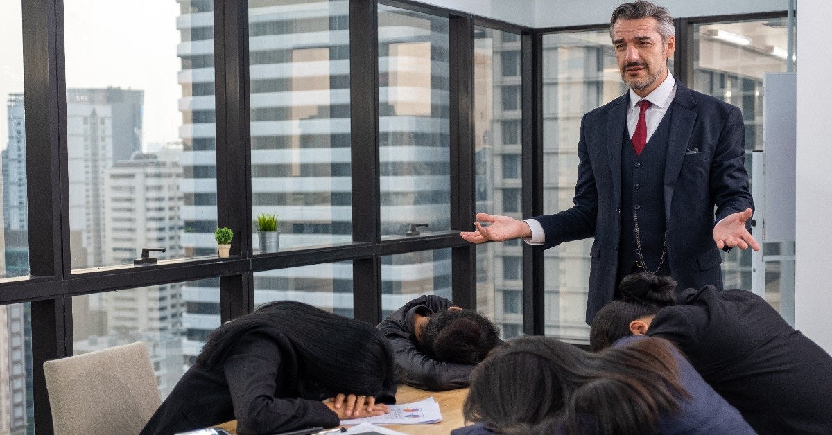 boss looking down at lazy colleagues sleeping on table