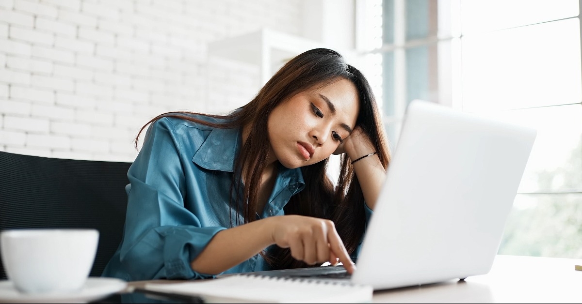 bored young asian woman typing laptop in office