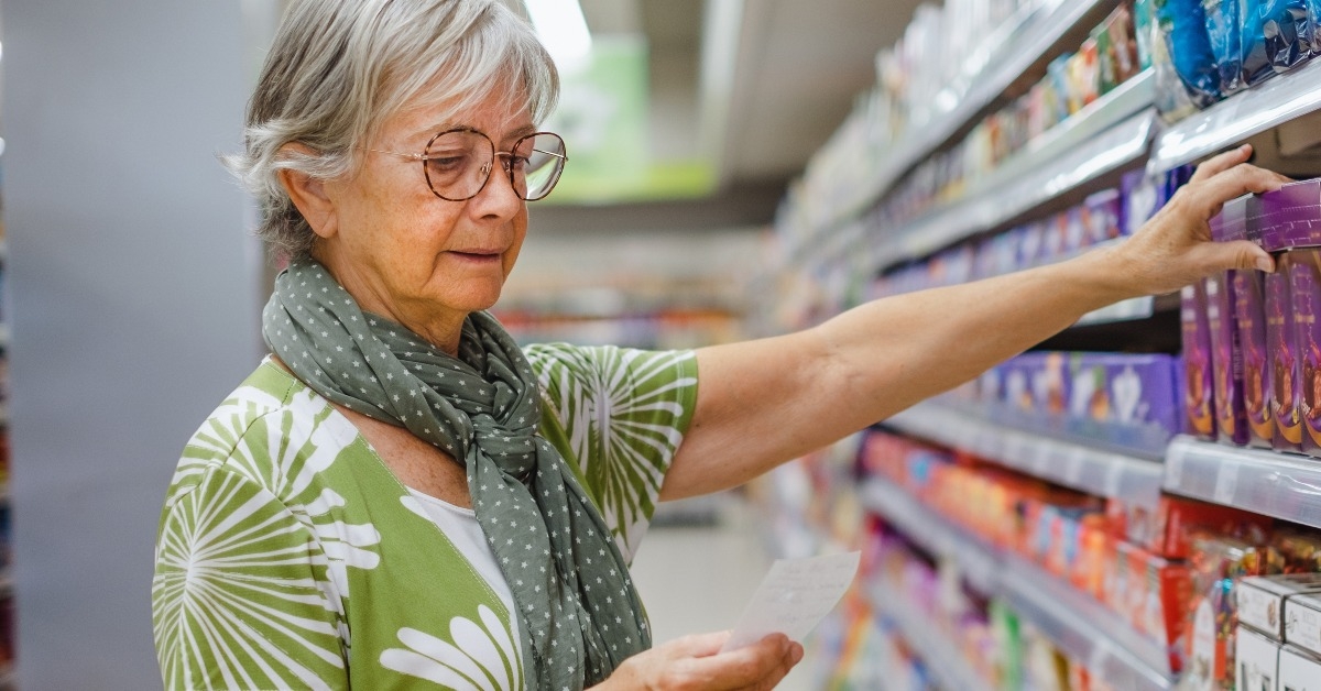senior woman selecting grocery items in a row of the supermarket