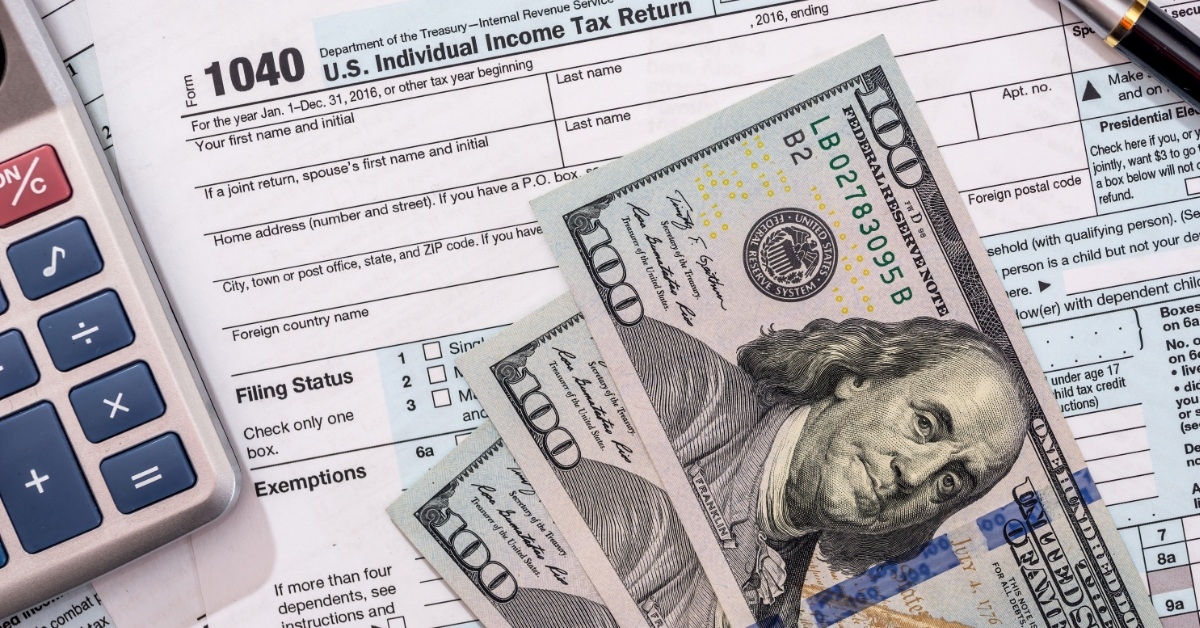 tax billing document with calculator and hundred dollar bills