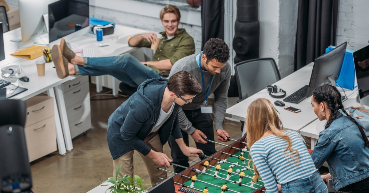 employees playing table soccer in workplace 