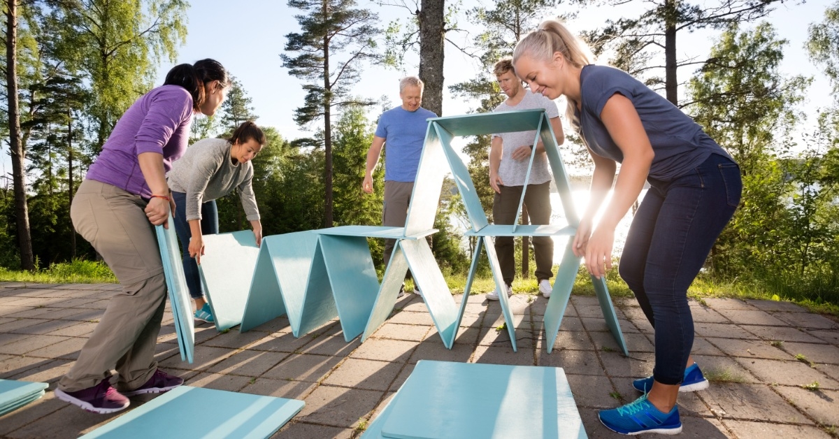 teamamtes making pyramids using blue planks on a patio